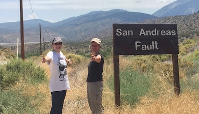 Researchers stand next to a sign that states "San Andreas Fault"