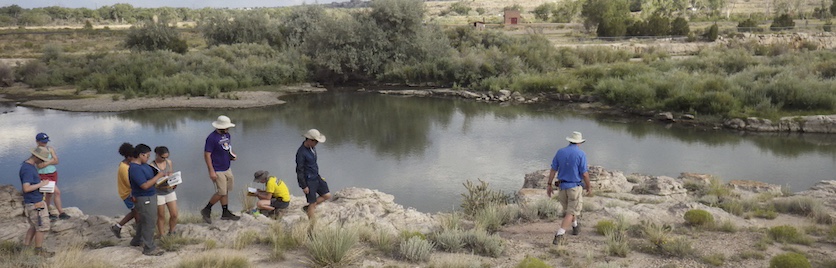 A group of students takes notes along a stream
