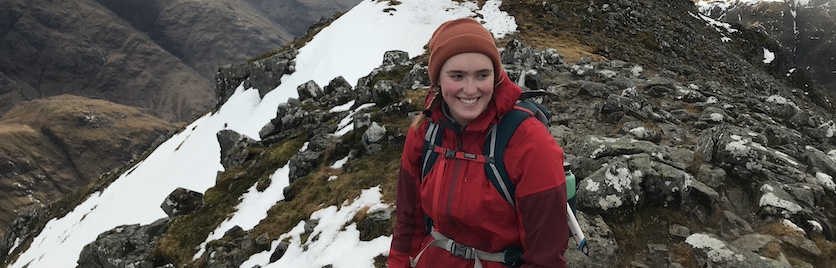 A student smiles on a mountaintop